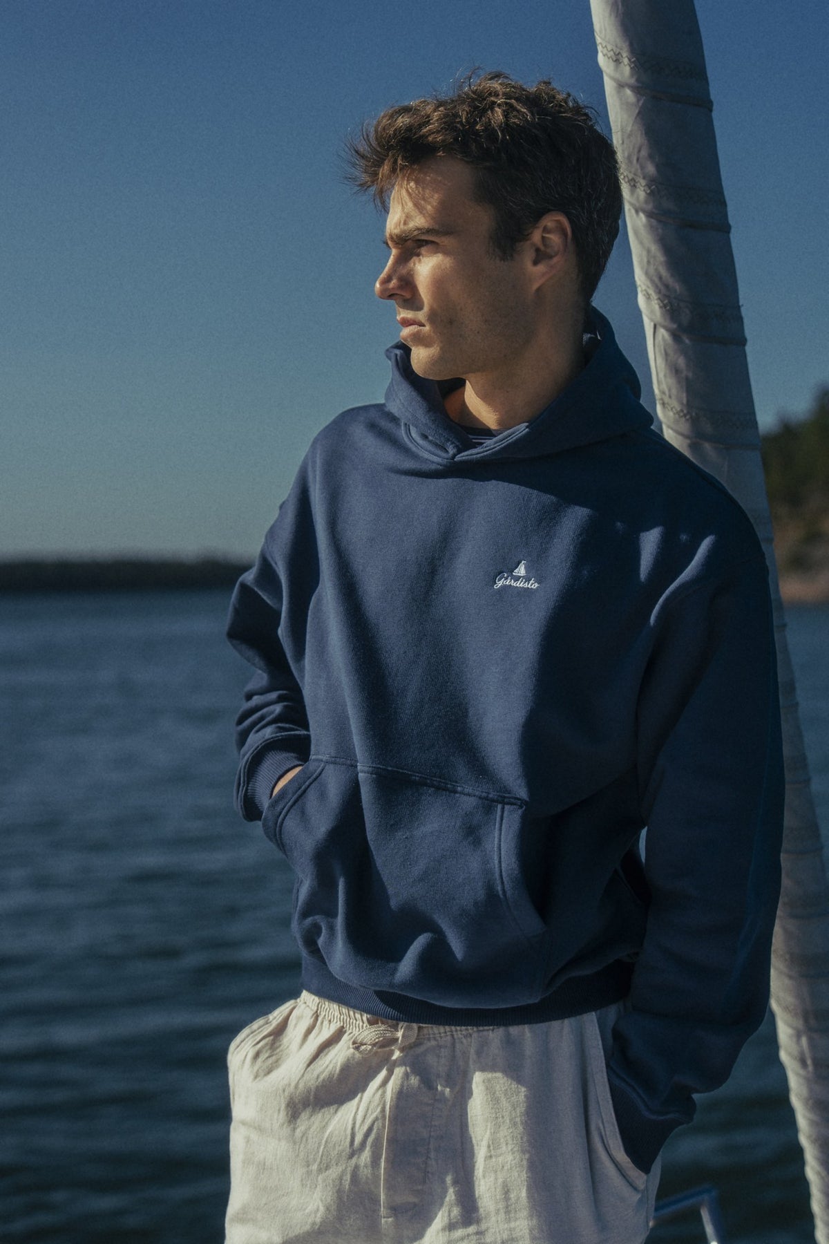 Person in a navy Gårdisto hoodie on the foredeck.