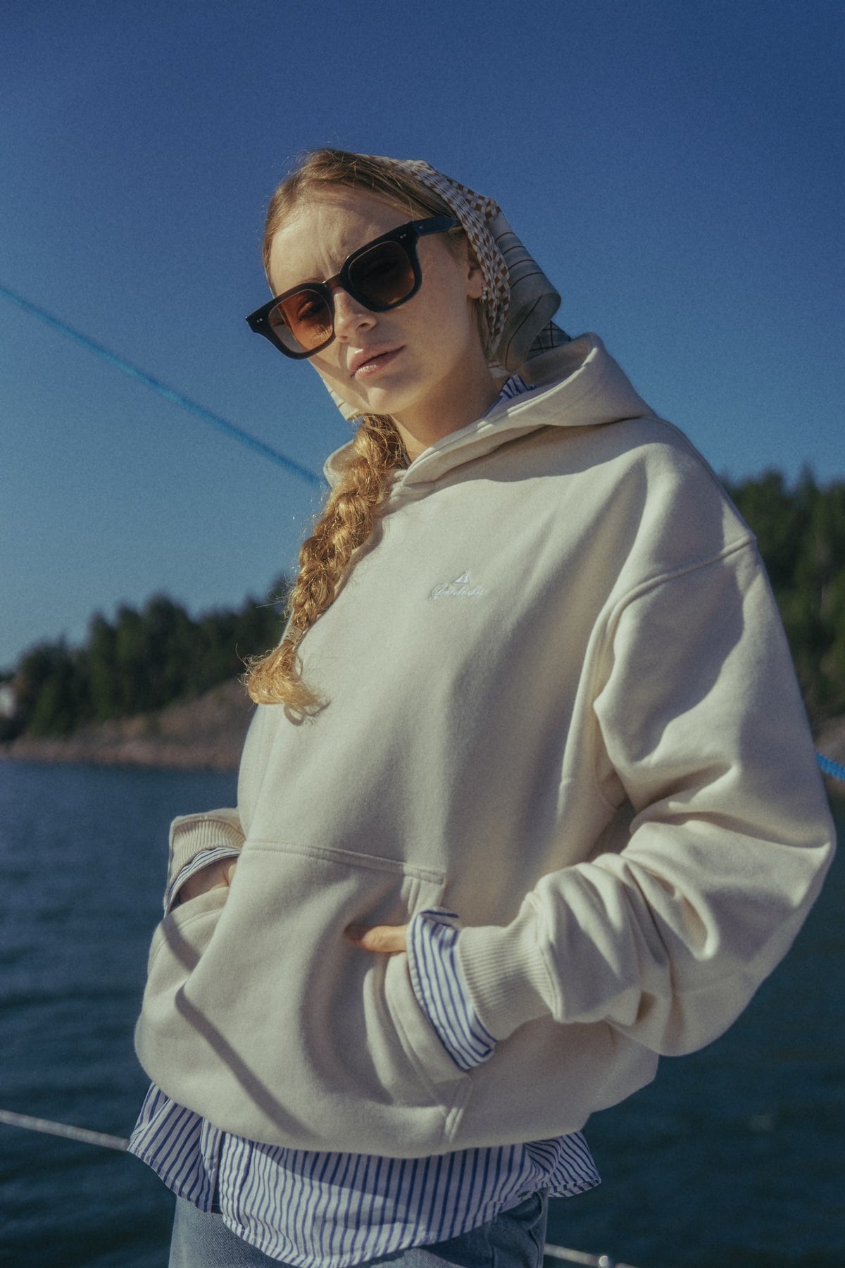 Person wearing a light-coloured Gårdisto hoodie on a sailing boat.