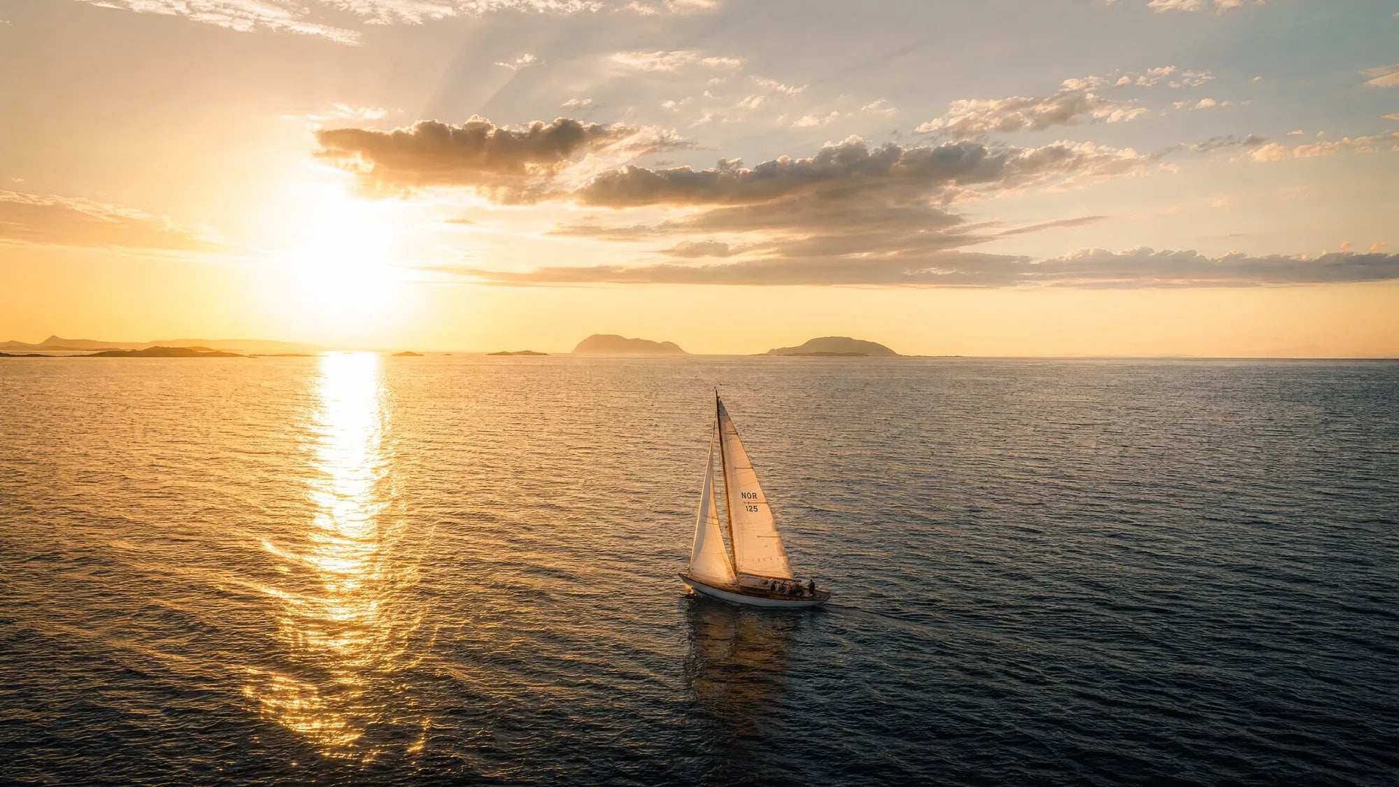 Seilbåt i den nordiske skjærgården ved solnedgang